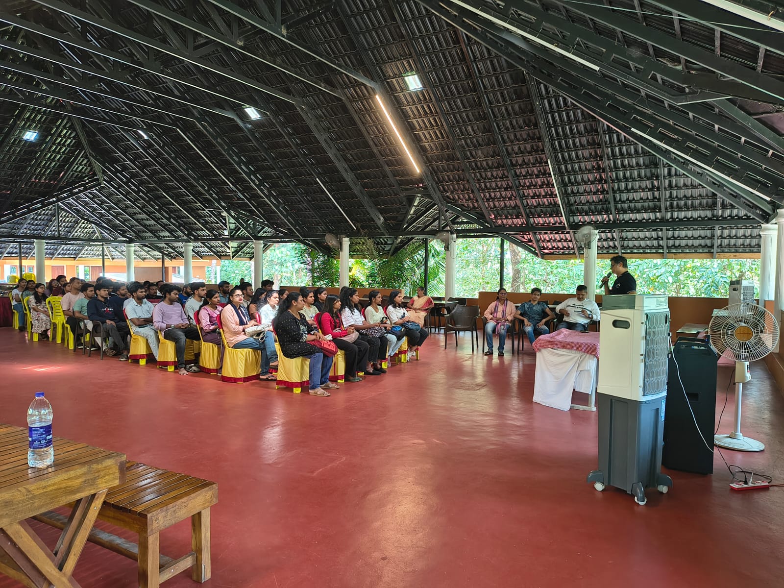 Team event underway in a large open hall with a speaker presenting